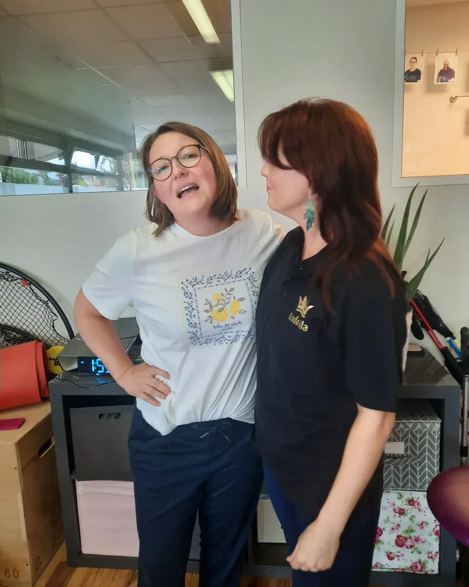 Zwei Kolleginnen lachen gemeinsam, eine trägt das schwarze Jubiläumsshirt